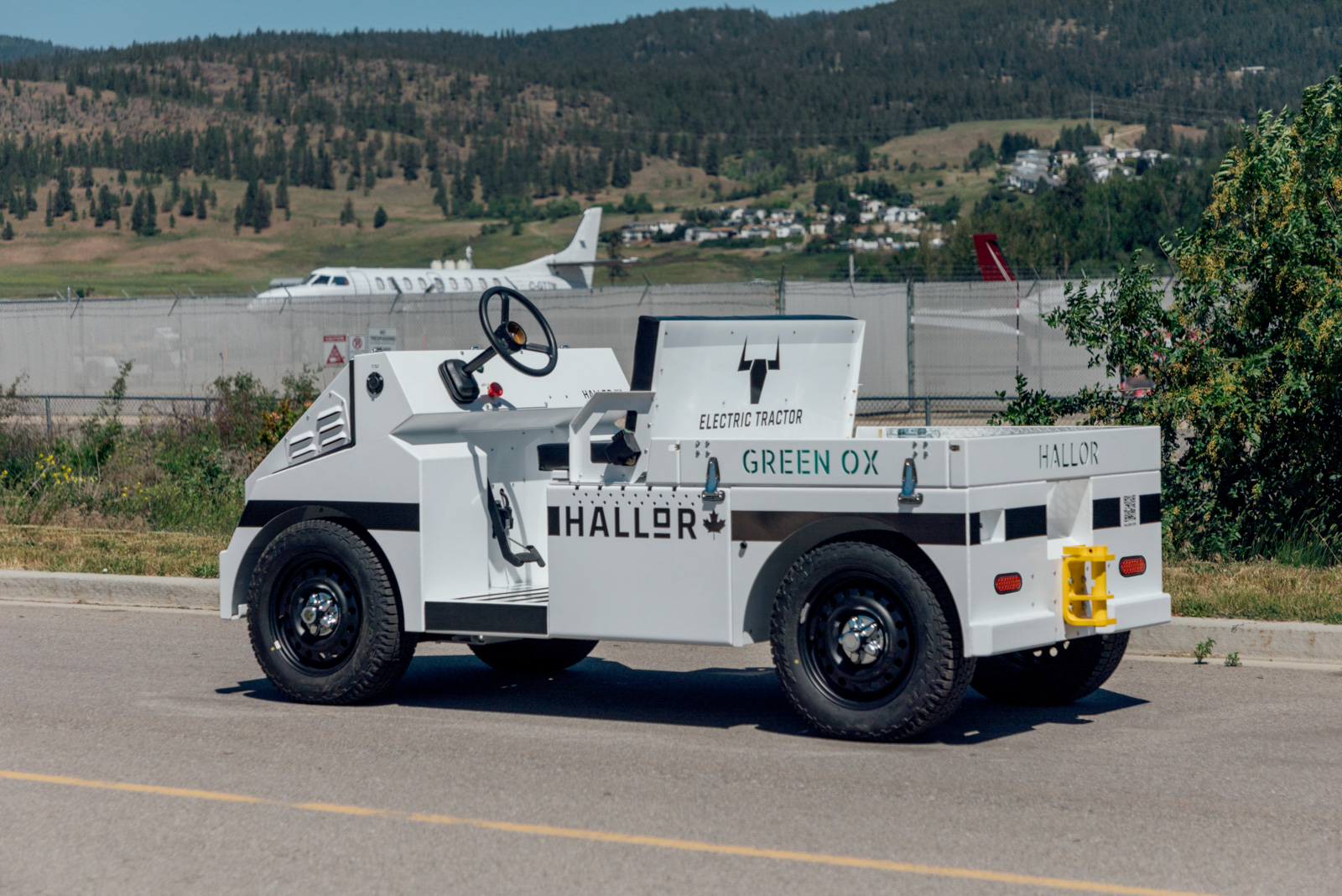 The Hallor Green Ox electric tractor in side profile, an aircraft behind